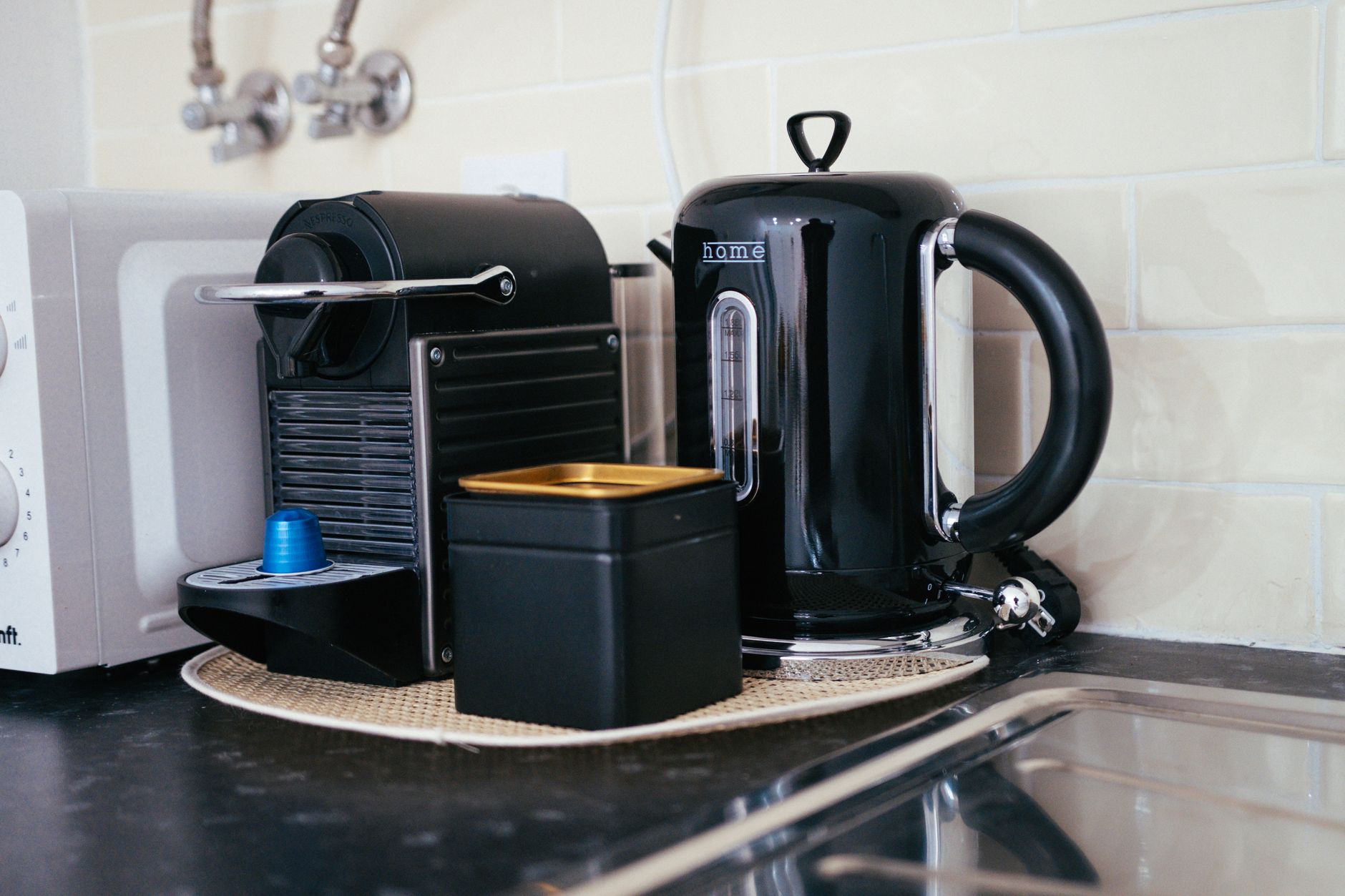 A compact home coffee corner with a coffee maker, mug, and small storage on a kitchen counter