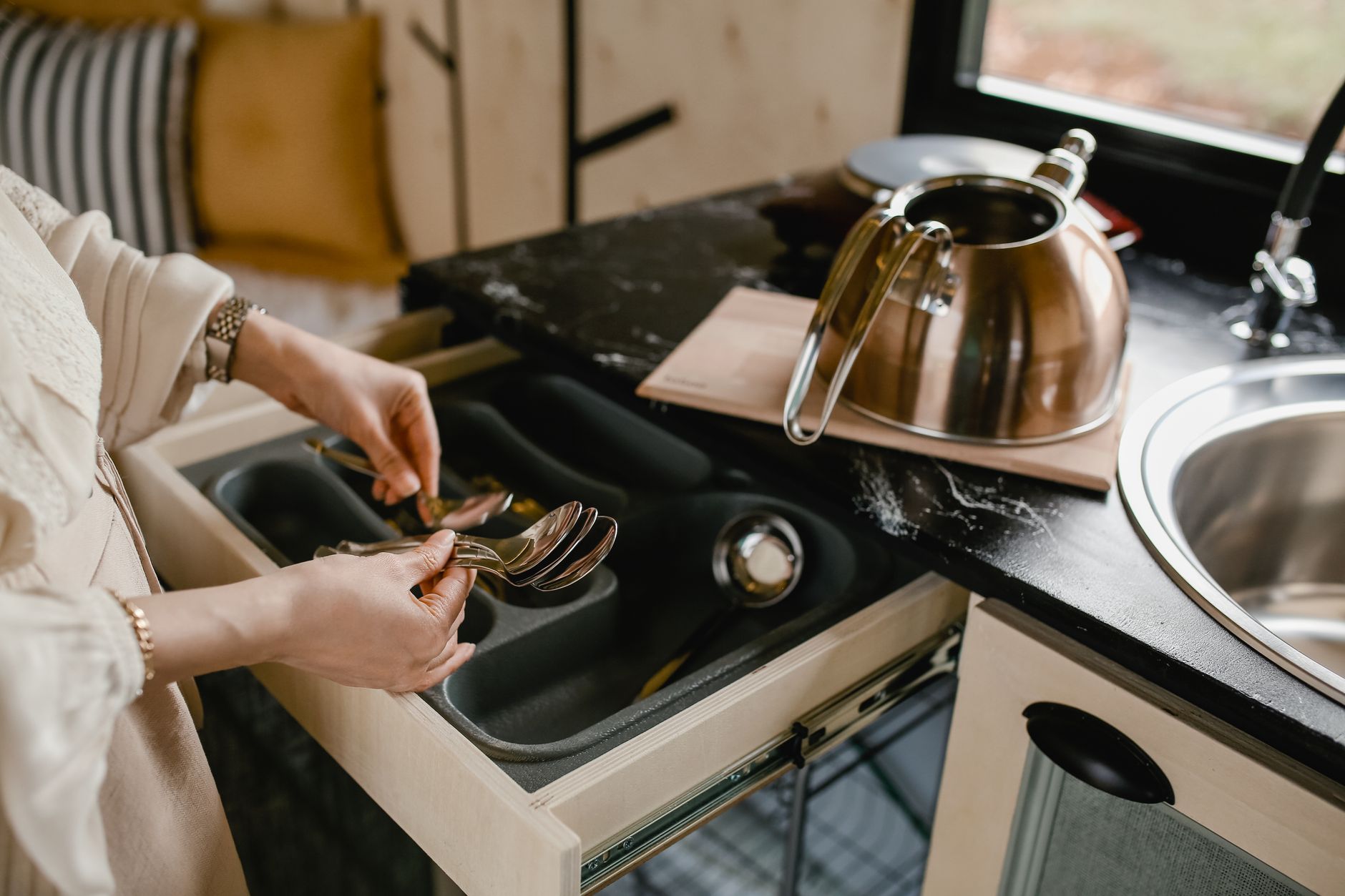 Neatly organized kitchen drawer with everyday items in a warm home setting