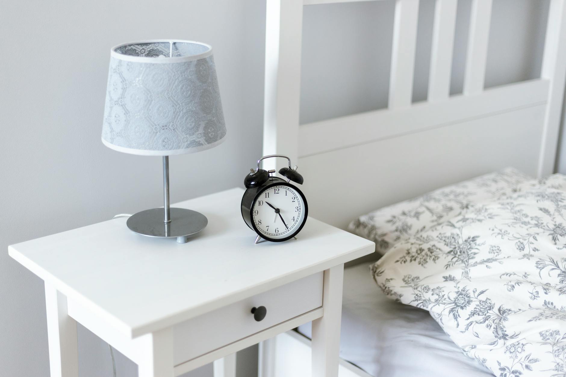 A neatly organized bedroom with a tidy nightstand, soft lighting, and a few personal items.